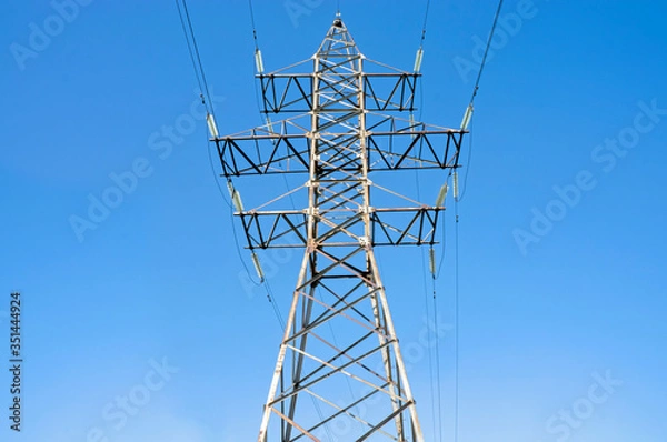 Fototapeta Pylon of an overhead power line (transmission pylon) against a blue sky