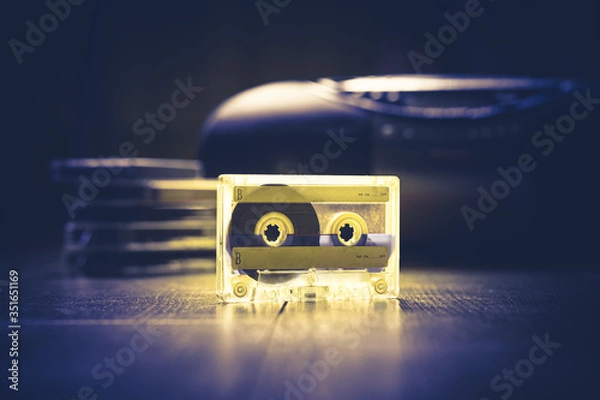 Obraz Transparent audio cassette tape lit by yellow and blue lamps. Retro tape recorder on the background. Retro audio. Hipster fashion concept