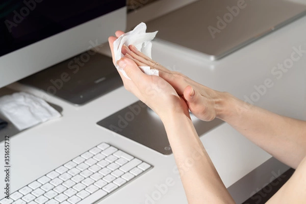 Fototapeta Close up of woman's hands in gloves wiping smartphone screen with disinfectant cloth
