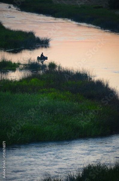 Fototapeta Slow river with dramatic clouds and trees around
