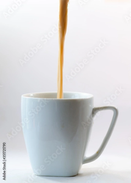 Fototapeta filling a cup with coffee and milk filling a cup with milk and coffee over the white background