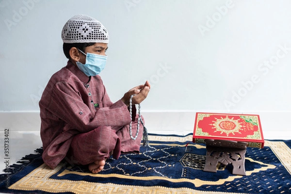 Obraz A little Asian Muslim boy is sitting and praying.