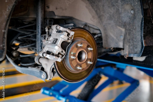 Fototapeta car automobile mechanic working on repairing the brake drum and disc vehicle, car in for service workshop for male car mechanic fixing problems replacing broken parts of using tools and equipment