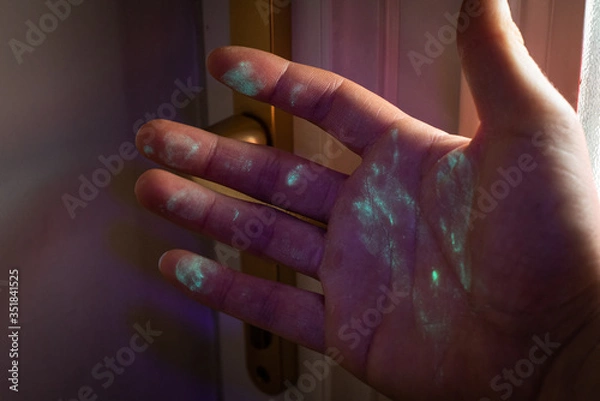 Obraz hand covered in bacteria or virus after touching door handle. Visualisation under UV light.