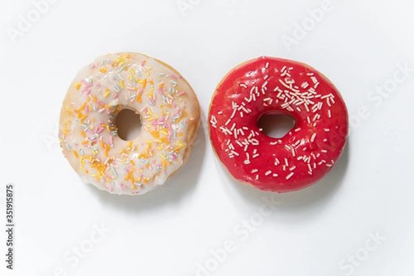 Fototapeta Donut day. Two bright colored donuts with colorful sprinkles on white background. Copy space, close-up
