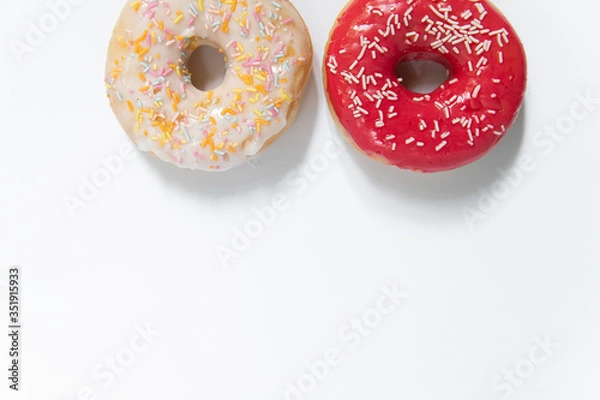 Fototapeta Donut day. Two bright colored donuts with colorful sprinkles on white background. Copy space, close-up