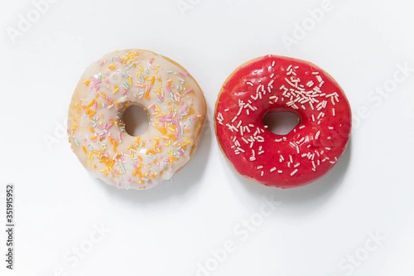 Fototapeta Donut day. Two bright colored donuts with colorful sprinkles on white background. Copy space, close-up