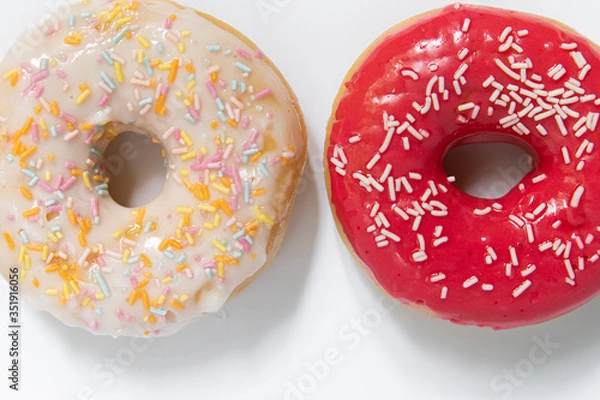 Fototapeta Donut day. Two bright colored donuts with colorful sprinkles on white background. Copy space, close-up