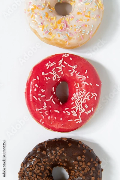 Fototapeta Assorted colored donuts in a row, minimalism on a white background, top view, close up