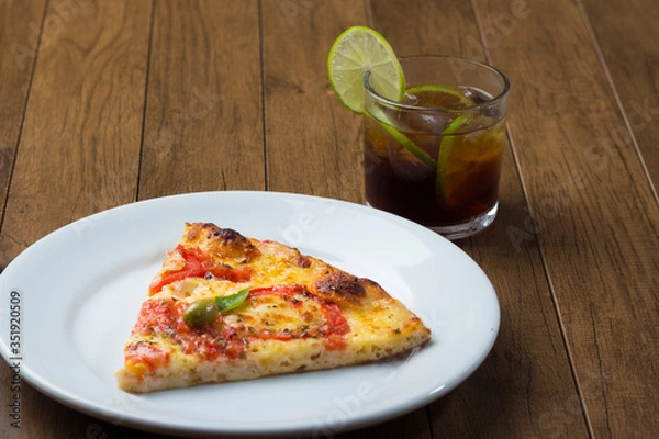 Fototapeta Tasty Slice of Pizza Marguerita made with Mozzarella Cheese, tomatoes, basil leaves and green olives. Served on the white plate. Cola and lemon soda.