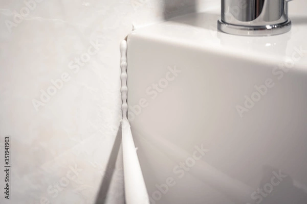 Obraz Detail of a cannula applying silicone to the seal of a bathroom sink
