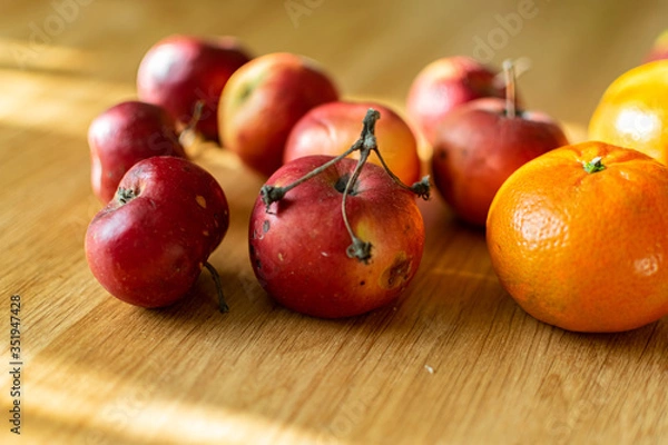 Fototapeta Bright juicy fruits, natural and natural fruits with damage. Red apples and tangerines on a modern brown light table