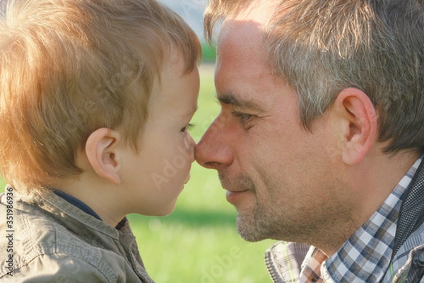 Fototapeta On father's day, a happy child is touching his dad with his nose close-up.