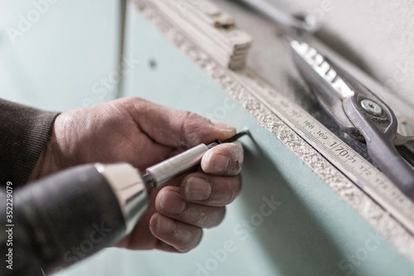 Obraz Eine Rigipsplatte wird mit Bohrmaschine und schraube befestigt