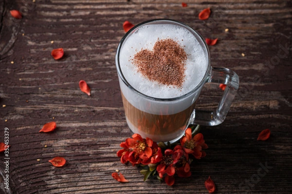 Fototapeta A glass with latte macchiato on wooden background with red flowers