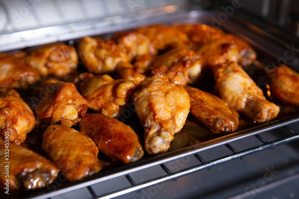 Fototapeta Chicken wings baked on a stainless steel tray in the microwave.