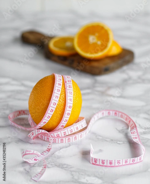 Obraz ripe orange wrapped with measuring tape