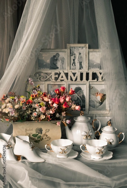 Fototapeta still life ceramic dishes with bow. flowes in a pot. Family photo frame.