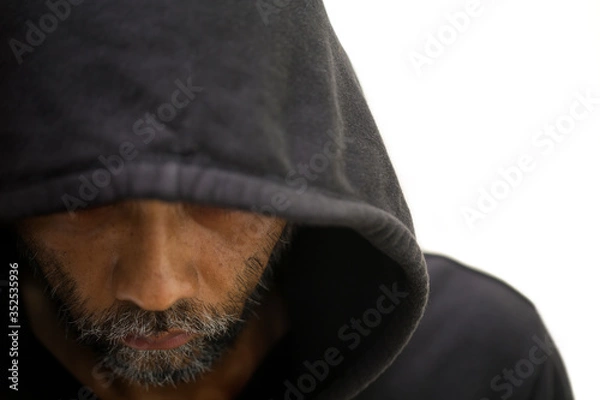 Fototapeta Close up of bearded middle aged man under the hood is bowing down to avoid eyesight on white background, concept of horror and Halloween