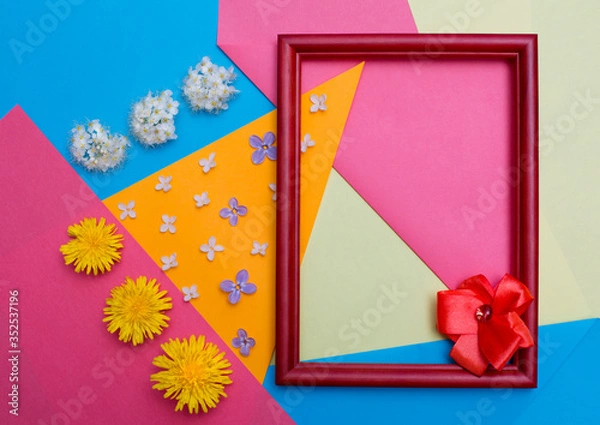 Obraz Frame and flowers lie on multi-colored paper.