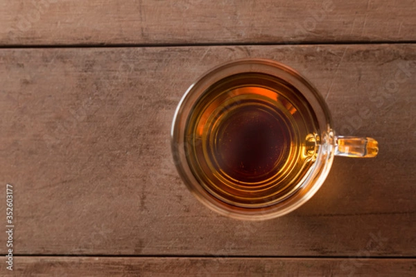 Fototapeta Close up top view hot tea cup on wood table . hot tea in handle glass with copy space for text or design.