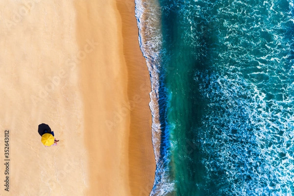 Fototapeta Aerial view of beach umbrella with a person sunbathing, at the Comporta Beach in Portugal. Concept for social distancing on the beach.