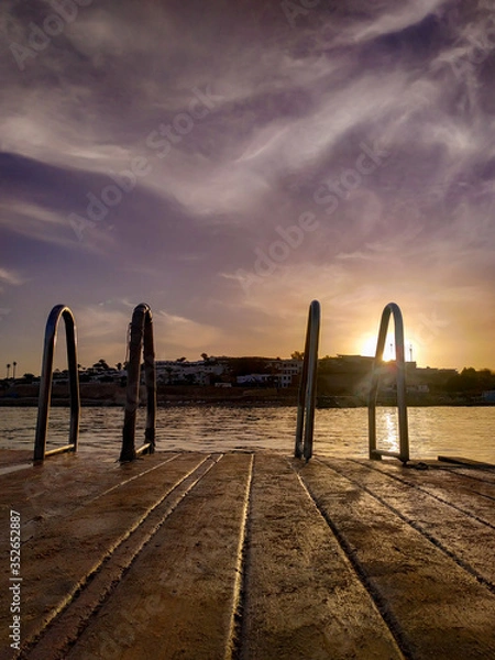 Fototapeta handrails for descent into the sea at sunset