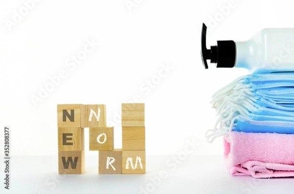 Fototapeta Conceptual new normal due to Covid-19. Wooden block stacked to form N with texts besides ace masks and  hand sanitizer. Selective focus on wooden cubes.