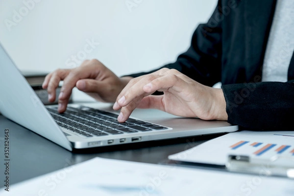 Fototapeta business female is sitting at a desk and calculating financial graph that show results