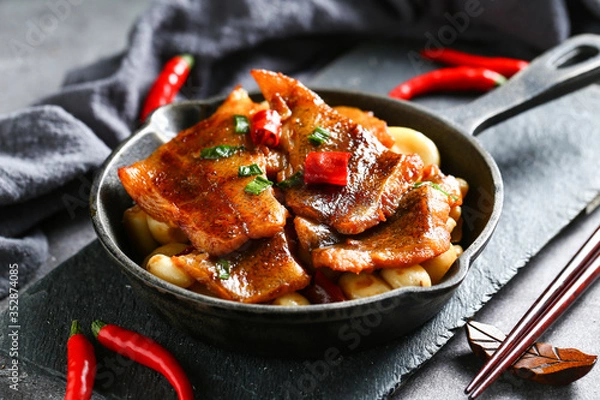 Fototapeta roasted flounder with pepper in pan on black stone board on dark background