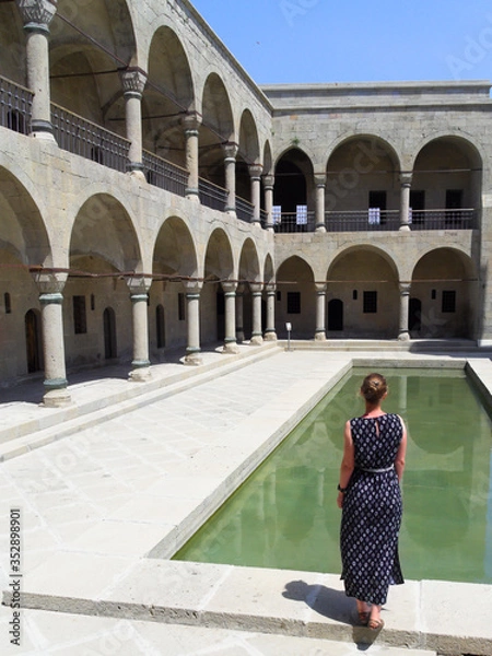 Fototapeta a woman stands against the background of an ancient building with her back turned