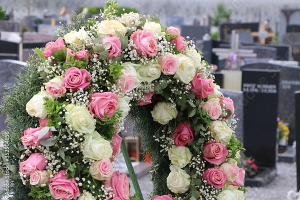 Fototapeta Blumenschmuck in Form eines Blütenkranzes mit Rosen nach einer Beisetzung auf einem Friedhof