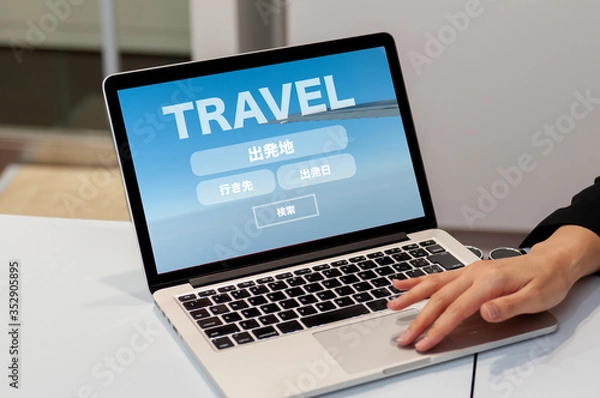Obraz GO TO TRAVEL キャンペーン　　Go Toキャンペーン
旅行のオンライン予約検索のイメージ　ノートパソコンで旅行の予約検索の画面を見せている女性の手