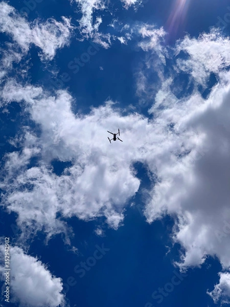 Fototapeta Latest technology drone or UAV shot in clear blue sky with some clouds