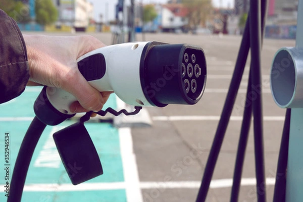 Obraz Power supply for electric car charging. Electric car charging station. Close up of the power supply plugged into an electric car being charged.