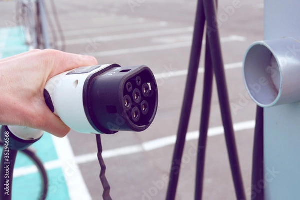 Obraz Power supply for electric car charging. Electric car charging station. Close up of the power supply plugged into an electric car being charged.