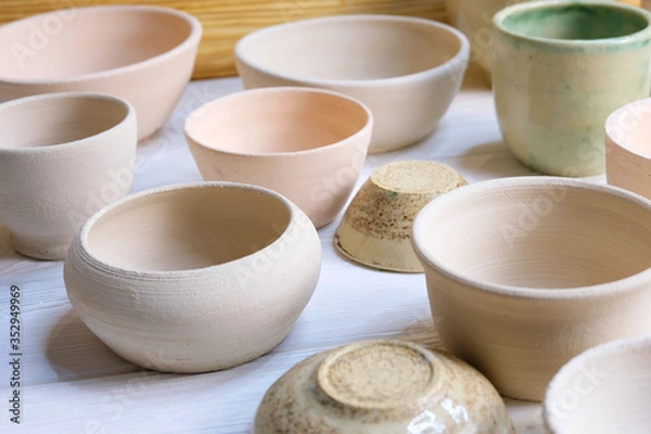 Obraz Modern pottery. Decorative ceramic, clay plate. Handmade light pottery.  Set of ceramic, bowls, cup with background.