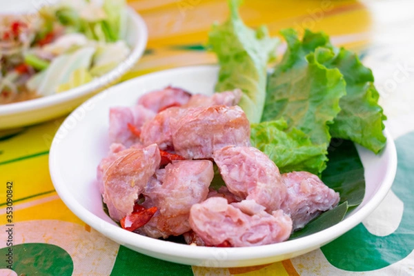 Fototapeta Sliced ferment sour pork served in dish wtih green lettuce and red chili.