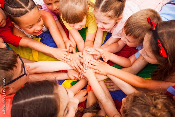 Fototapeta Children holding hands together, laying on a floor