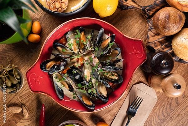 Fototapeta mussels in a creamy sauce with microgreens on a wooden table. top view