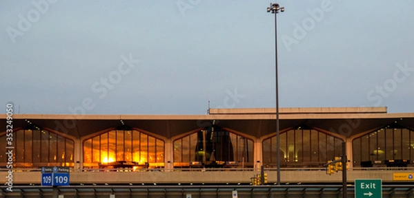 Fototapeta sunset orange light reflecting on windows of terminal building in Newark Airport