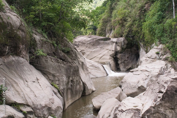 Fototapeta Huge rock formations formed by streams of water and a small waterfall.