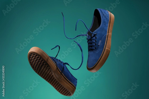 Obraz Close up view of levitation blue sneakers shoes with  flying laces over green background with copy space for text. 