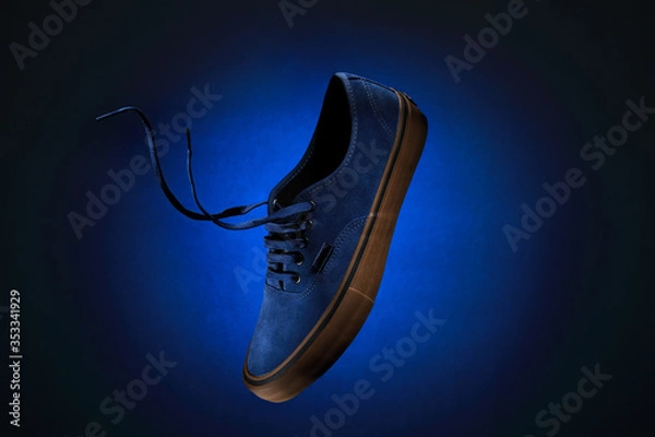 Obraz Close up view of levitation blue sneakers shoe with  flying laces over blue background with copy space for text. 