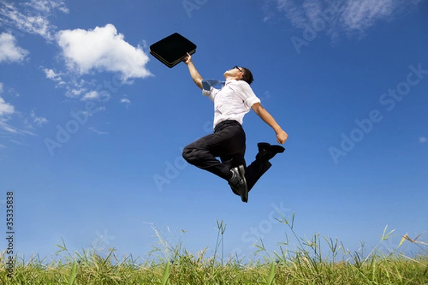 Obraz happy and successful businessman jumping on the field