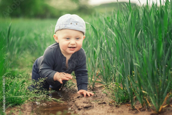 Obraz A Caucasian infant climbs in a muddy puddle.