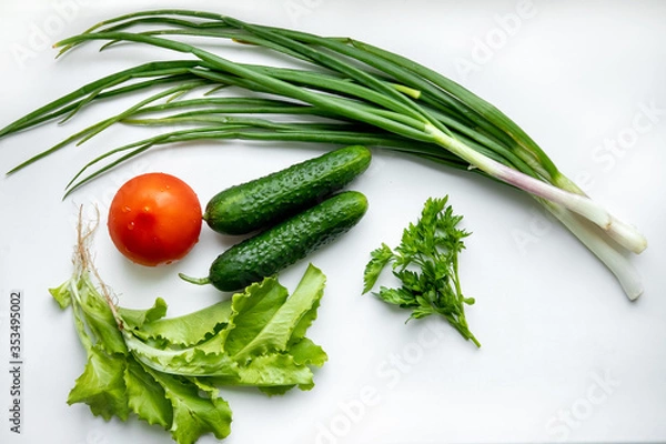 Fototapeta Fresh green vegetables and tomatoes on a white background