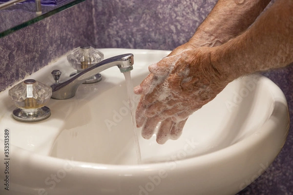 Fototapeta Rubbing hands with soap running water in bathroom sink