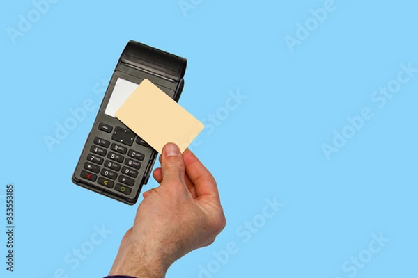 Fototapeta The hand holds a credit card on the payment terminal. Isolated on blue background