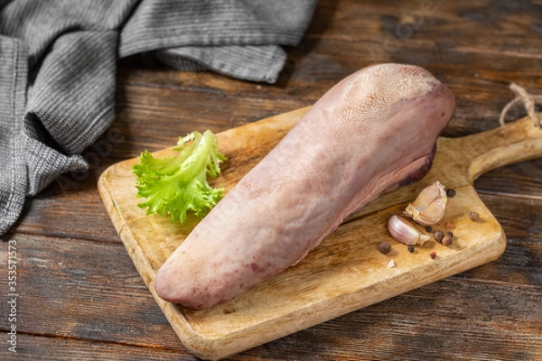 Obraz Beef tongue on a wooden Board on a brown wooden table. Raw beef tongue on the kitchen table. Rustic style